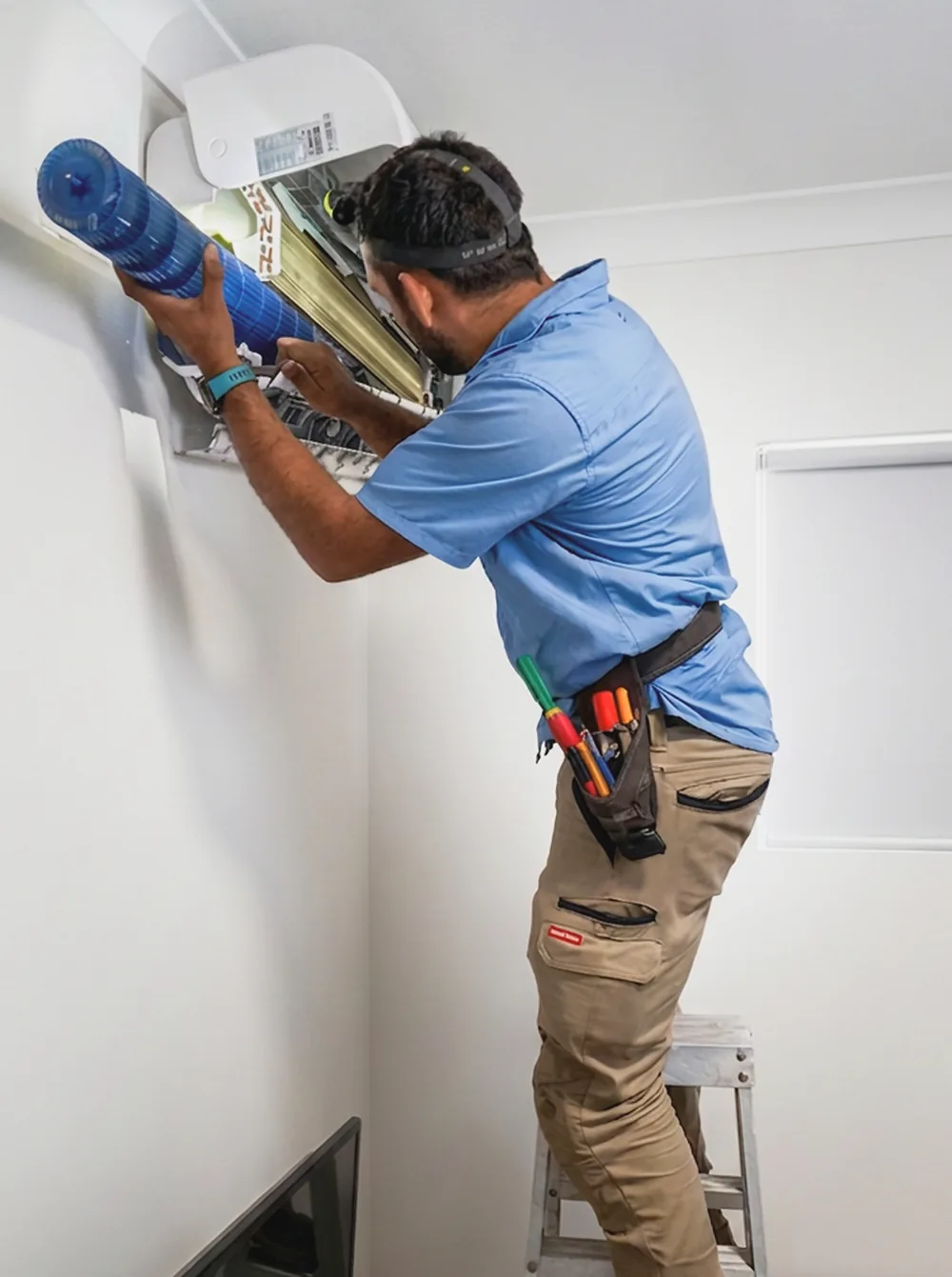 AuzAir technician servicing a wall-mounted air conditioner